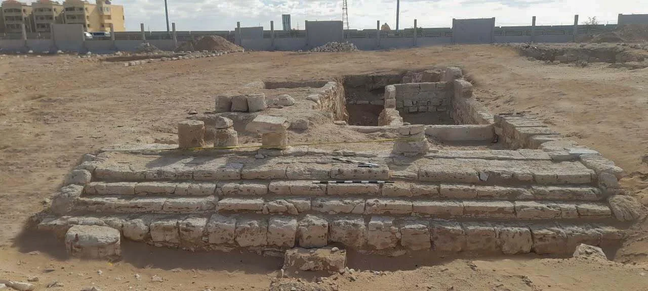 A series of stone ruins in a sandy desert.